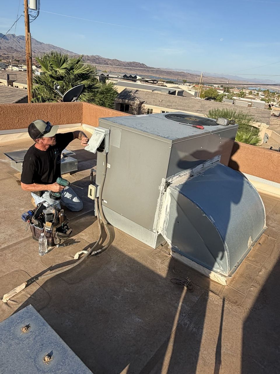 Air-Exx technician servicing a rooftop package unit above Lake Havasu City, Arizona
