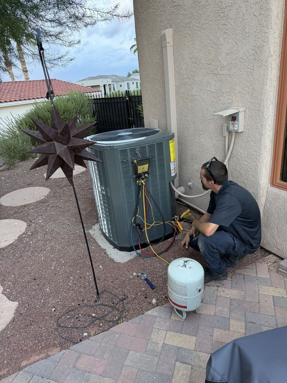 Air-Exx technician checking refrigerant charge with manifold gauges on a Trane condenser