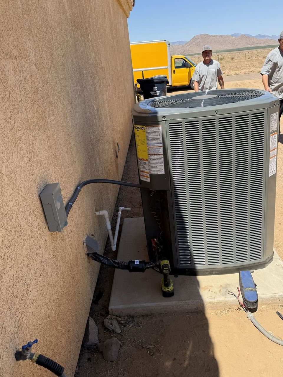 Two Air-Exx technicians setting a new Trane condenser at an Arizona home