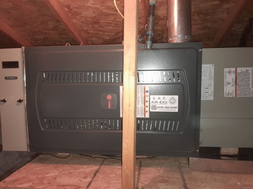Trane furnace in an attic with an Air-Exx service sticker and phone number