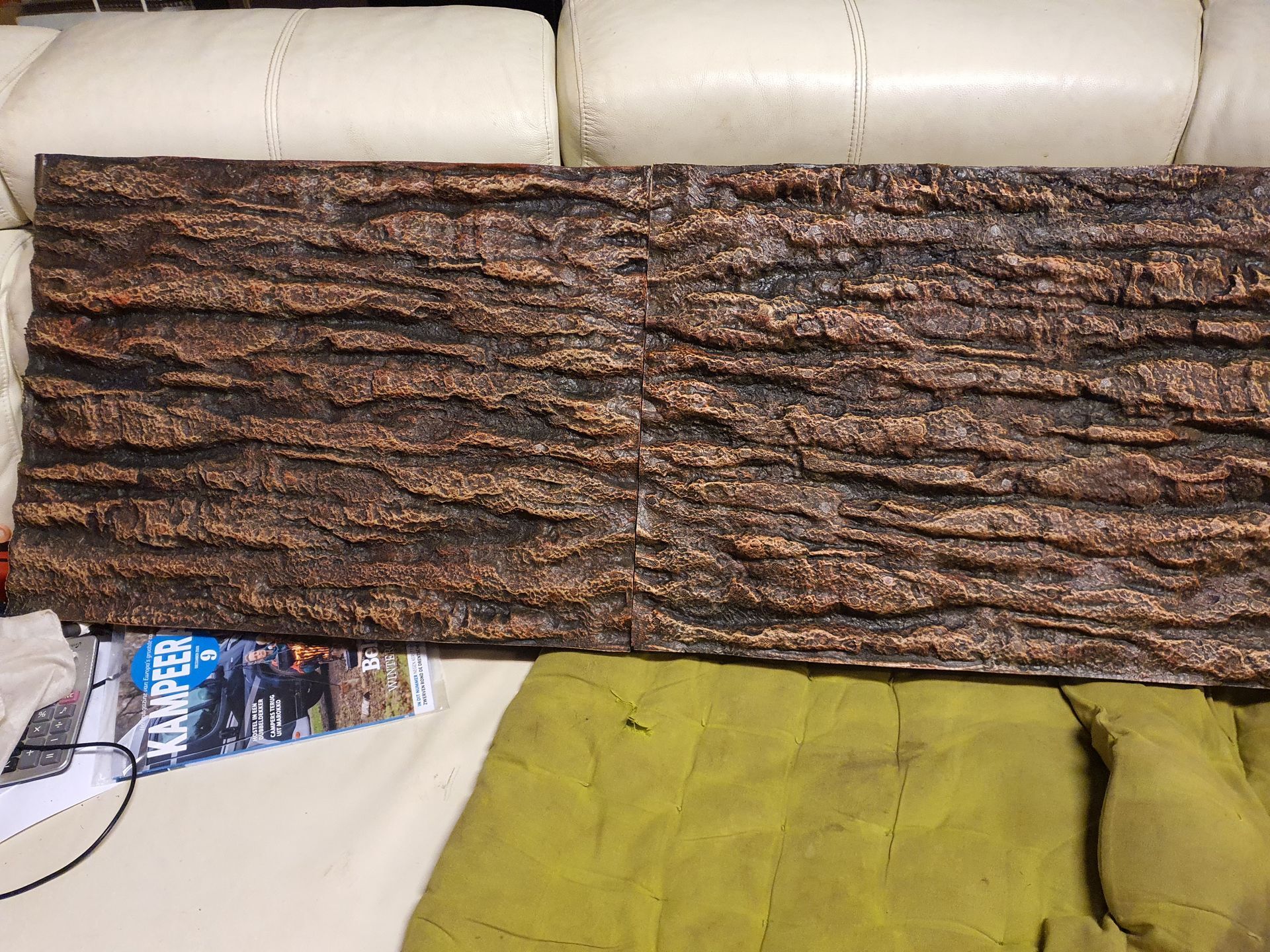 Op een bed ligt een stuk hout naast een tijdschrift.