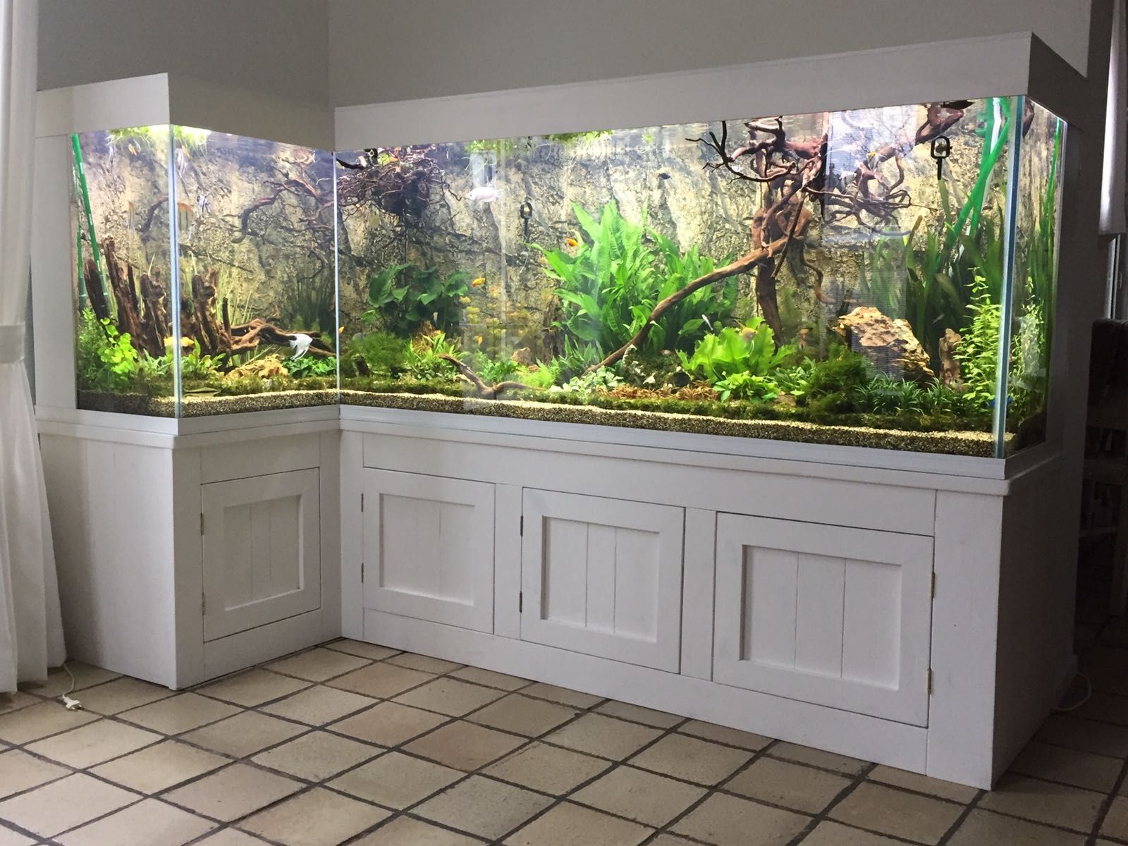 In een kamer met tegelvloeren staat een groot aquarium.