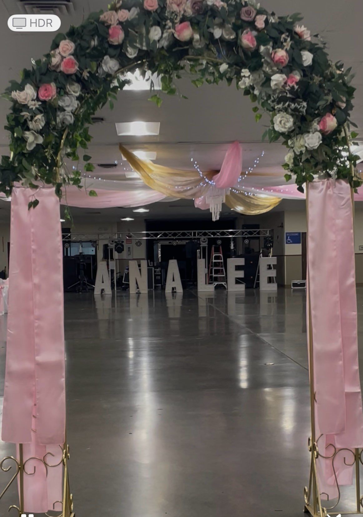 Floral archway with pink draping, leading to the name 