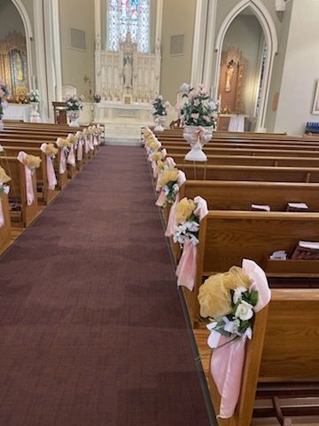 Church aisle with floral pew decorations, leading to an altar.