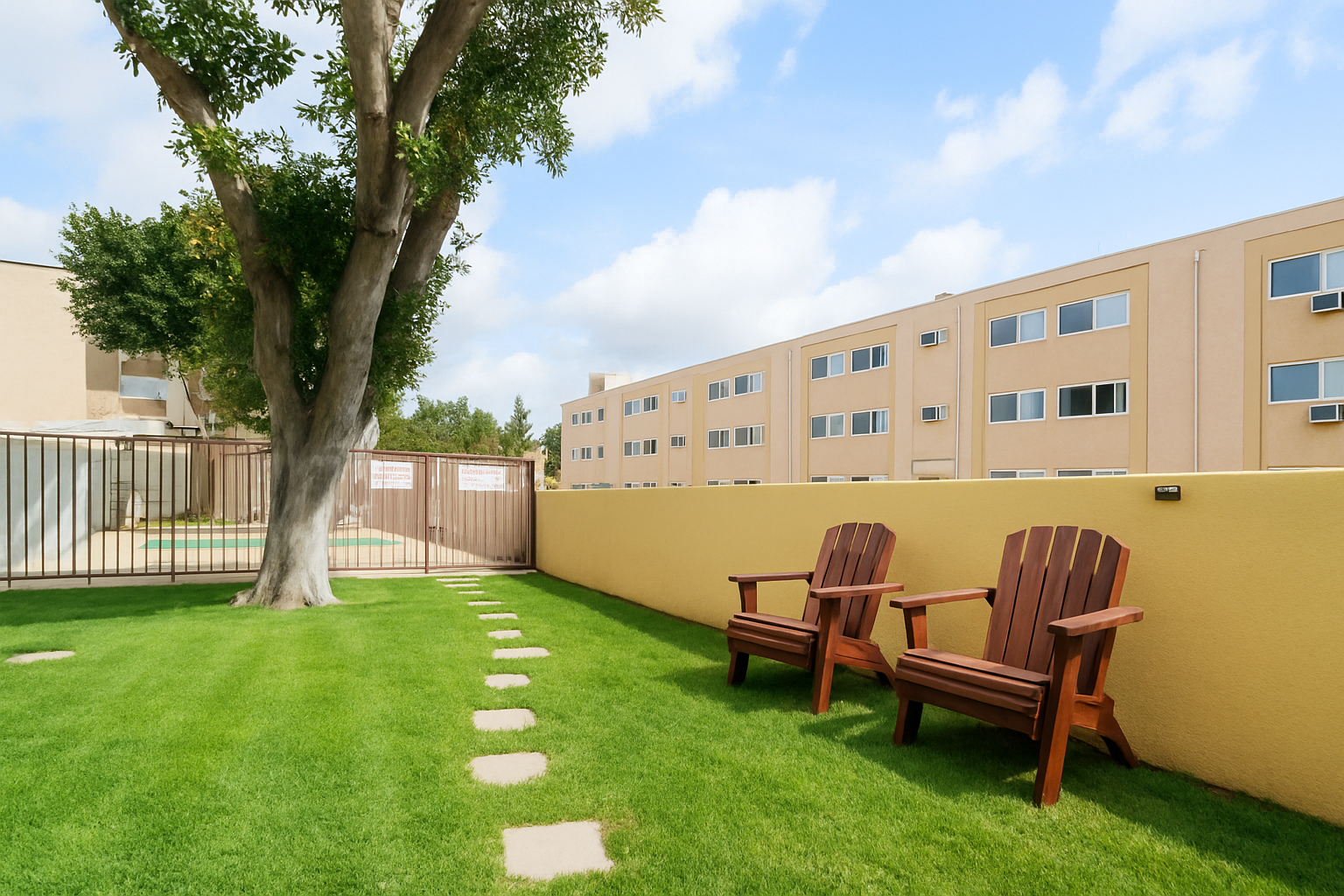 Two wooden chairs on a grassy lawn with a pathway, next to a building.