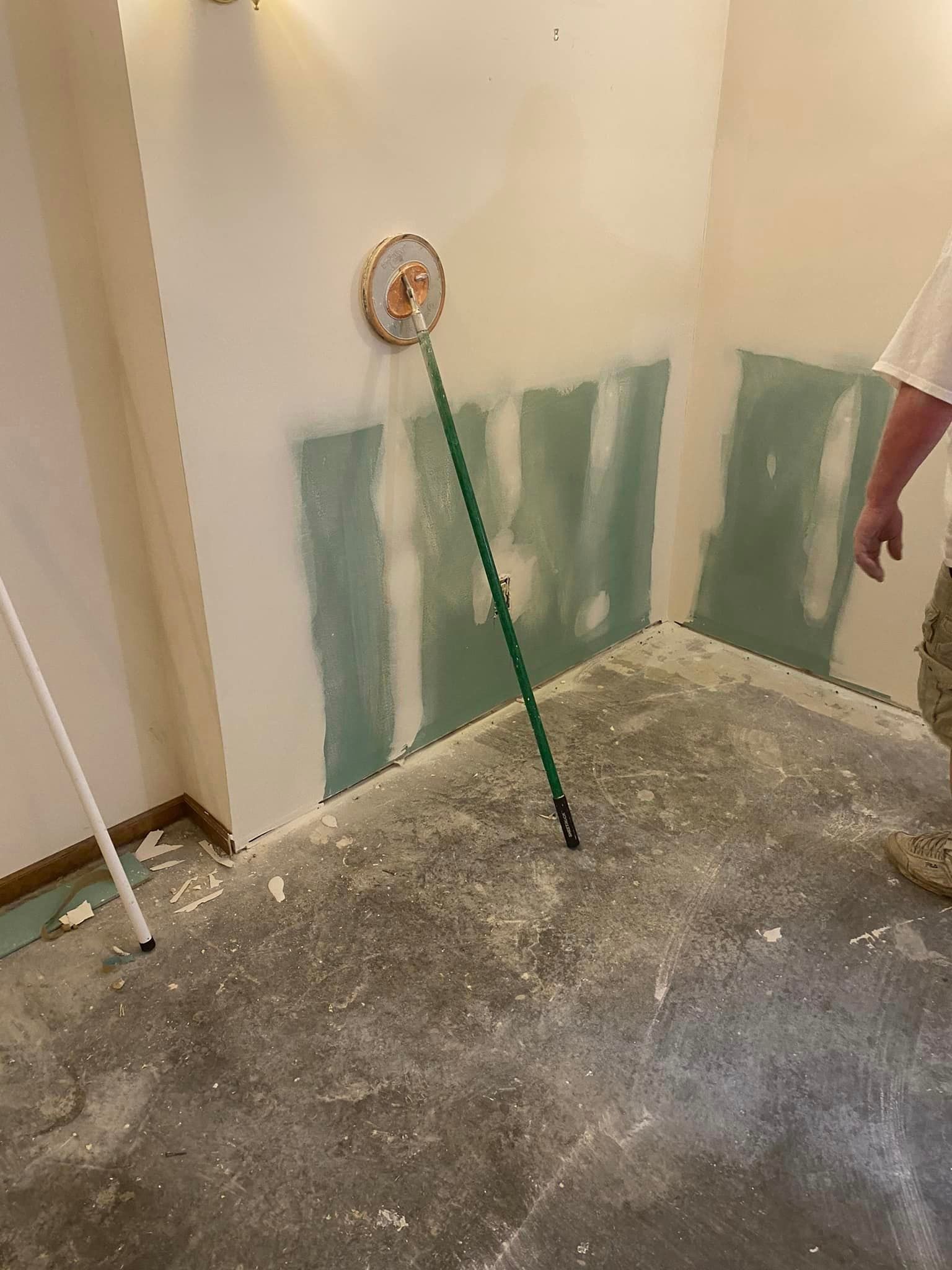 A man is standing in a room with a broom on the floor.