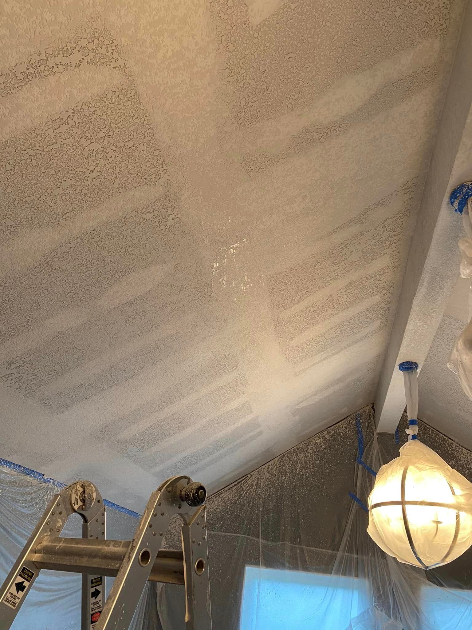 A room with a ladder and a light hanging from the ceiling.