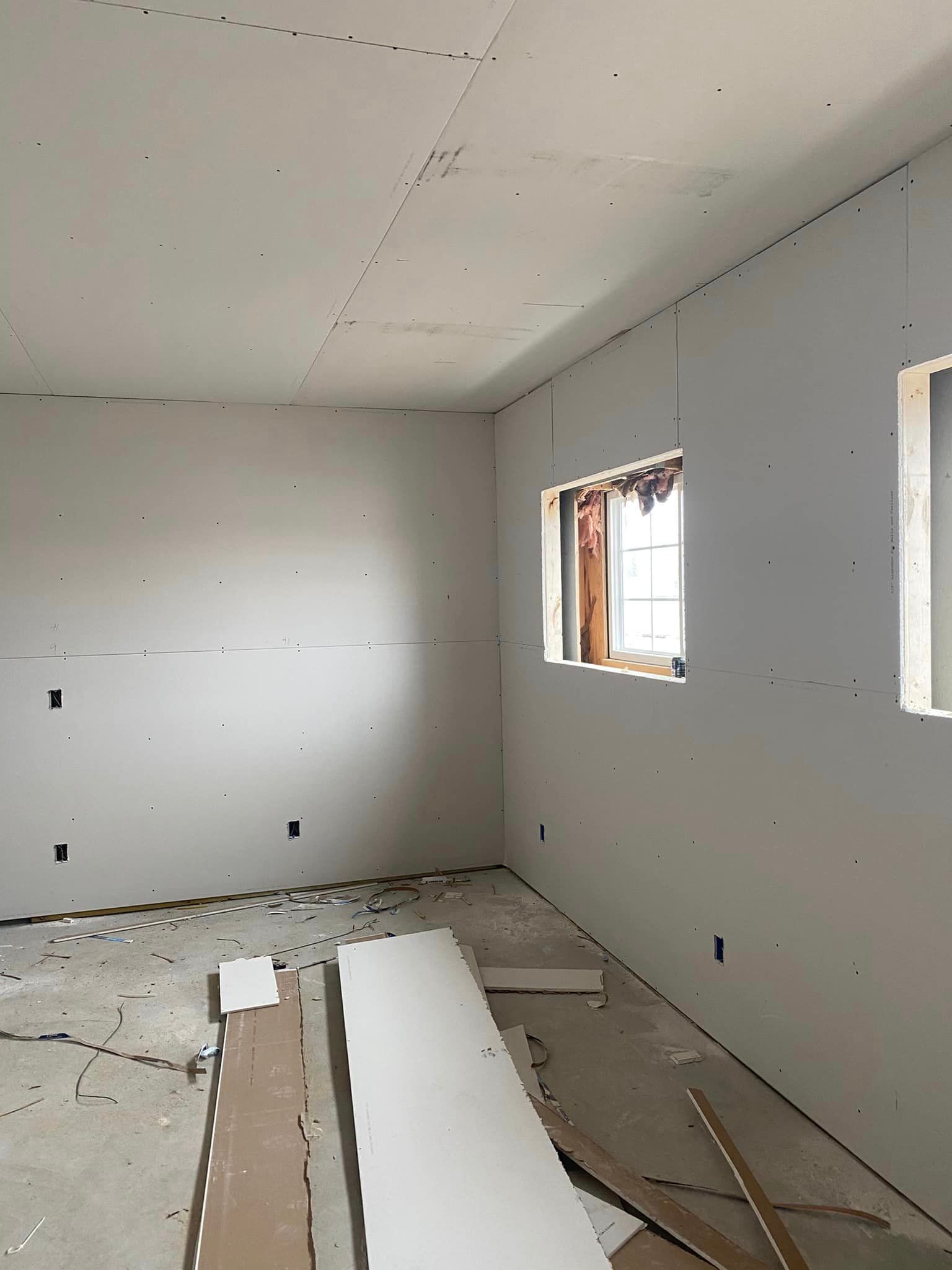 A room that is being remodeled with drywall and windows.