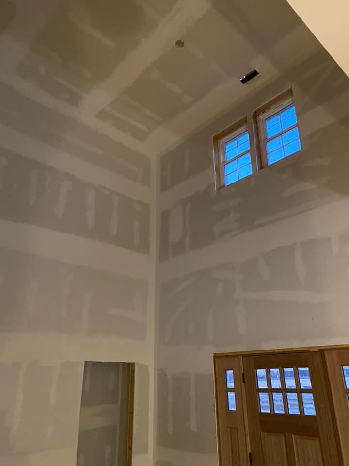 A room with a lot of drywall and a door.