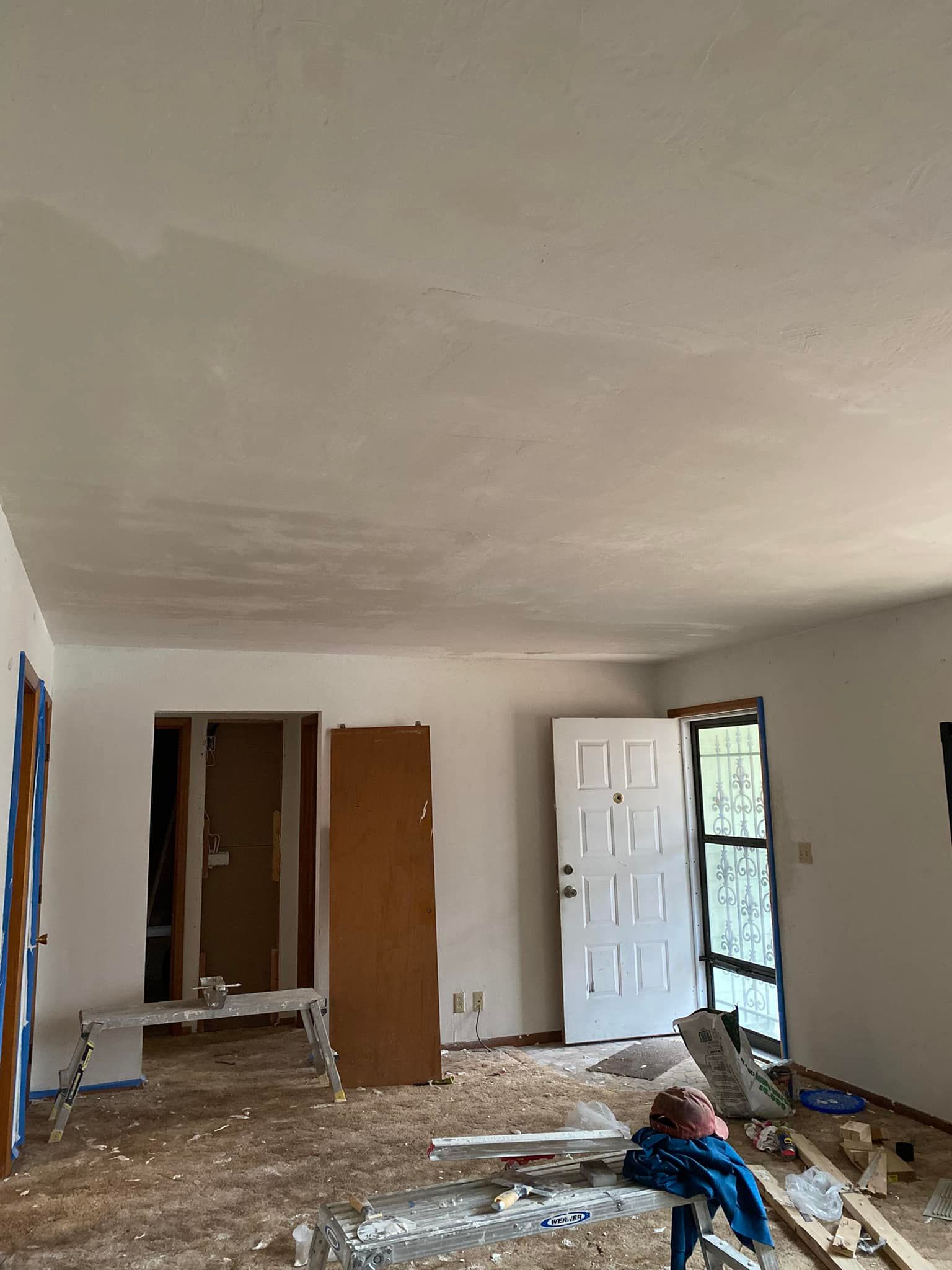 A living room with a ceiling that is being painted and a door that is open.