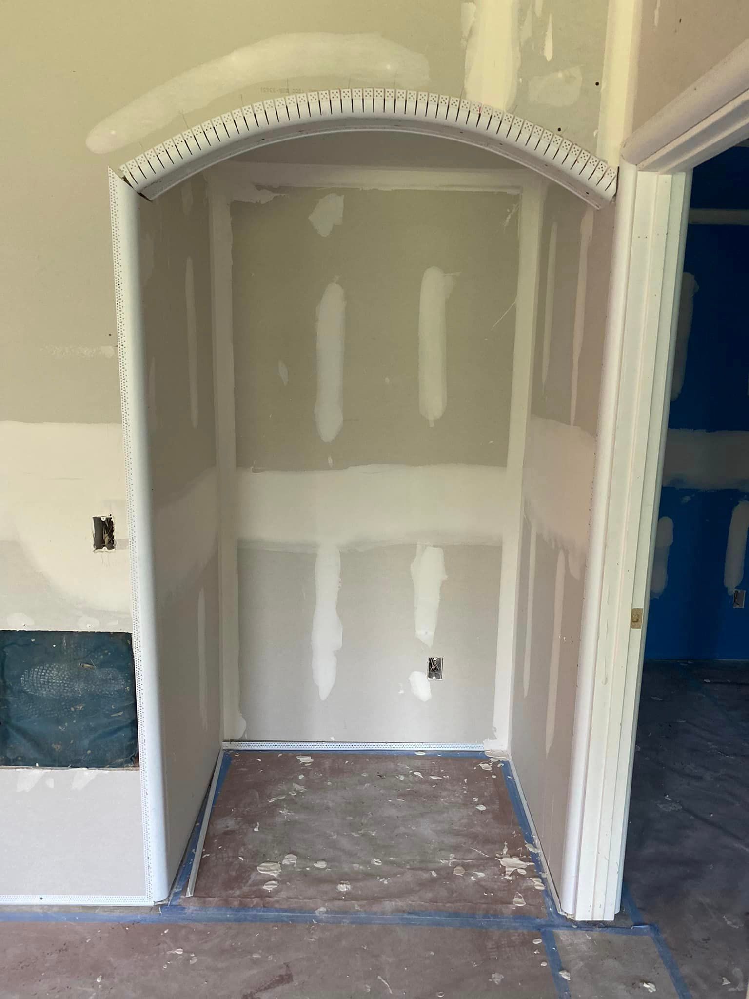 A room with a door and a wall that is being remodeled.