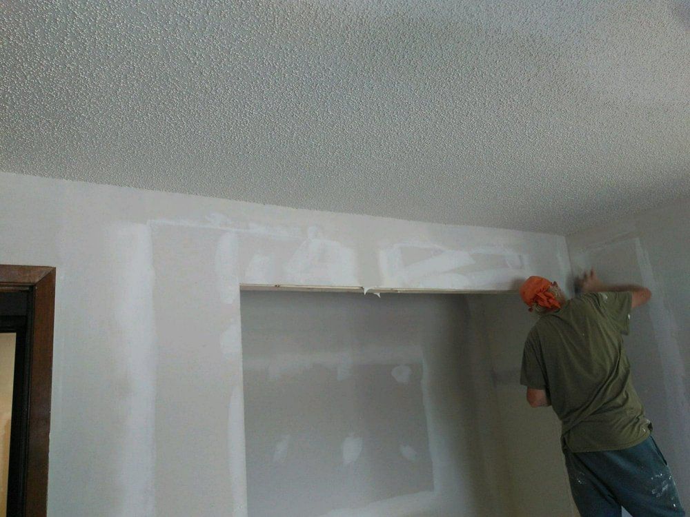 A man is plastering a wall in a living room.