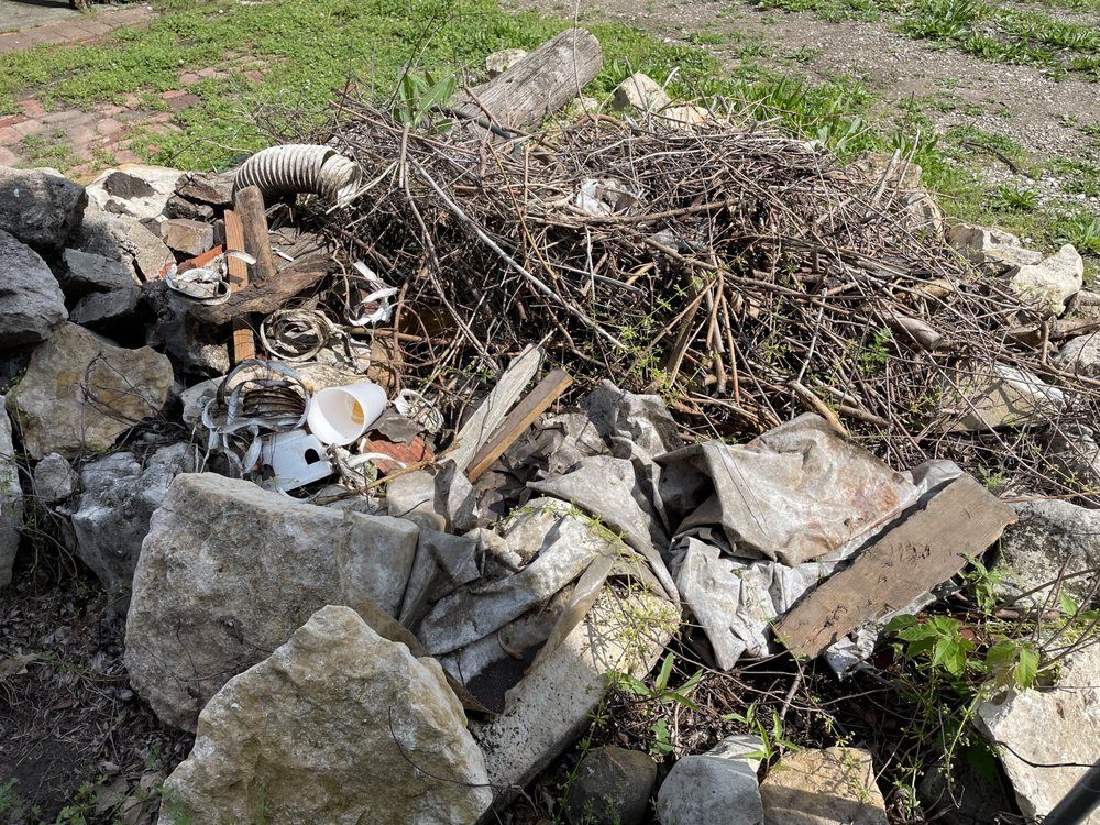 There is a pile of rocks and branches in the grass.