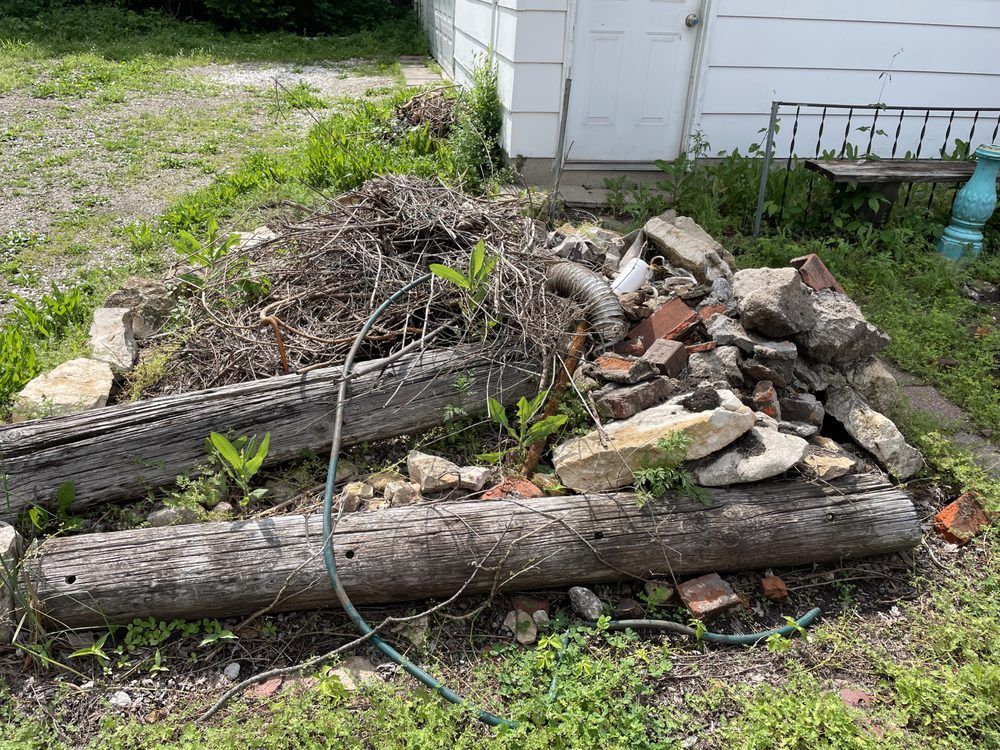 A pile of rocks and logs is sitting in front of a white house.