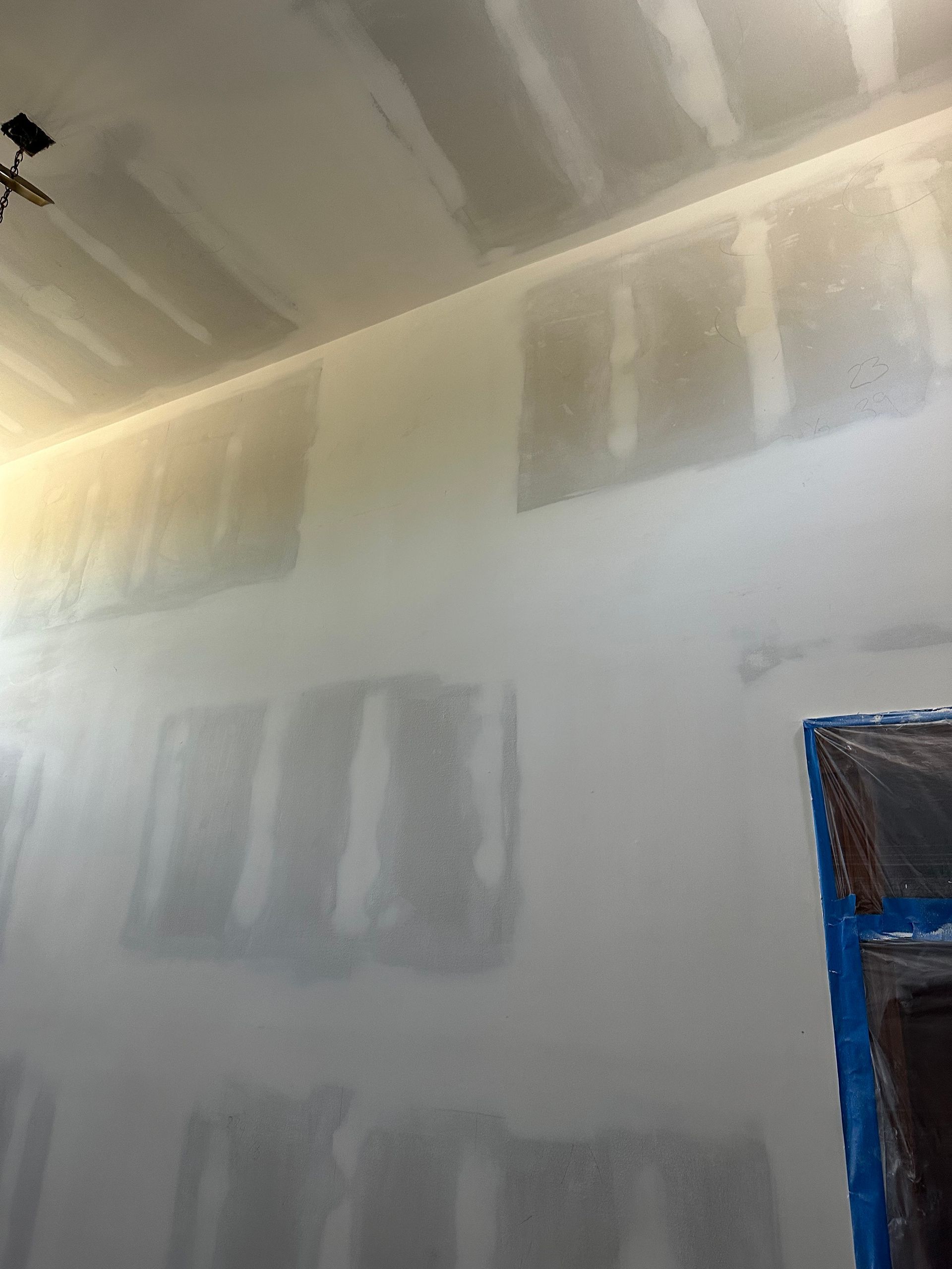 A room with a ceiling fan and a lot of drywall on the walls.
