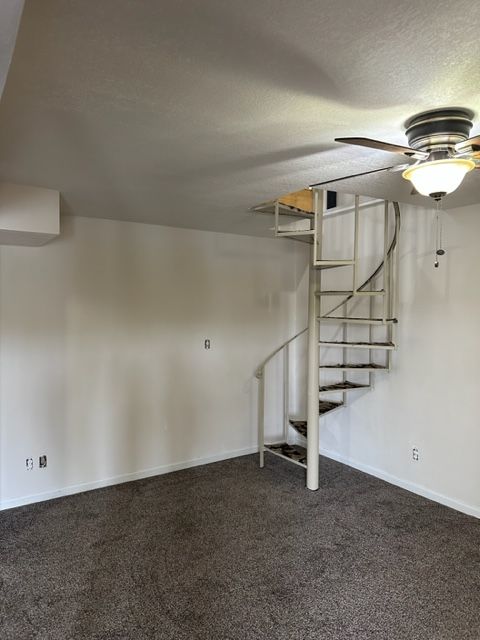 An empty room with a spiral staircase and a ceiling fan.