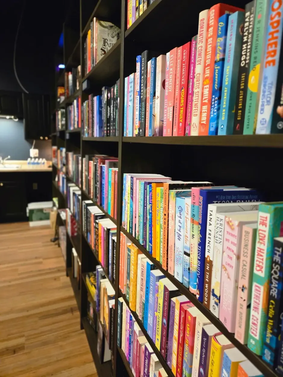 Bookshelves lined with colorful books in a bookstore aisle with wooden flooring