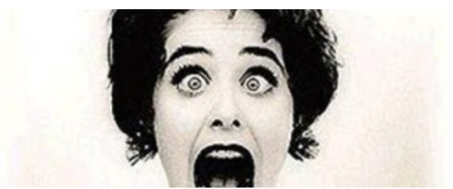 Woman with wide eyes and open mouth, screaming in fright.
