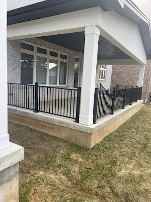 There is a porch with a black railing and a white roof.