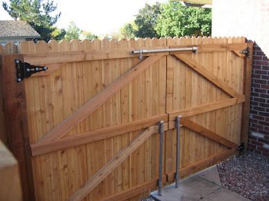 A wooden gate with a brick wall in the background