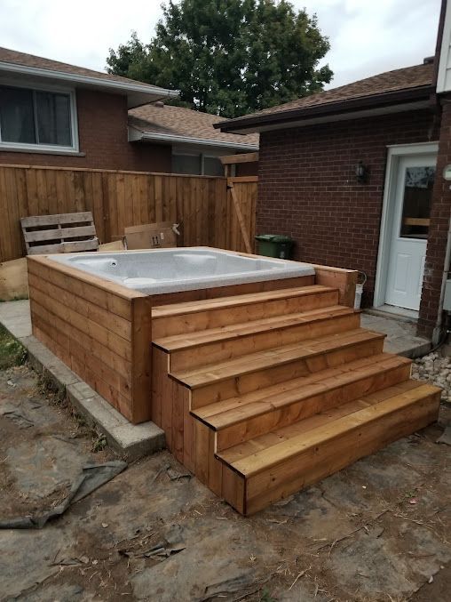 A wooden deck with stairs and a hot tub in the backyard of a house.