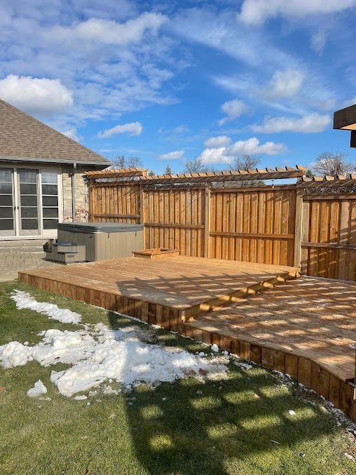 A wooden deck with a pergola and a hot tub in the backyard of a house.