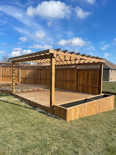 A wooden pergola is sitting on top of a wooden deck in a backyard.