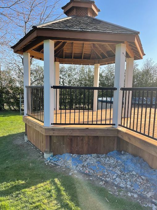 A gazebo with a wooden deck and a metal railing