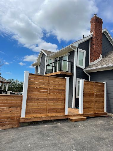 A house with a wooden deck and a wooden fence in front of it.
