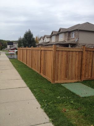 A wooden fence along a sidewalk next to a row of houses.