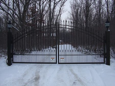 A black wrought iron gate is open in the snow