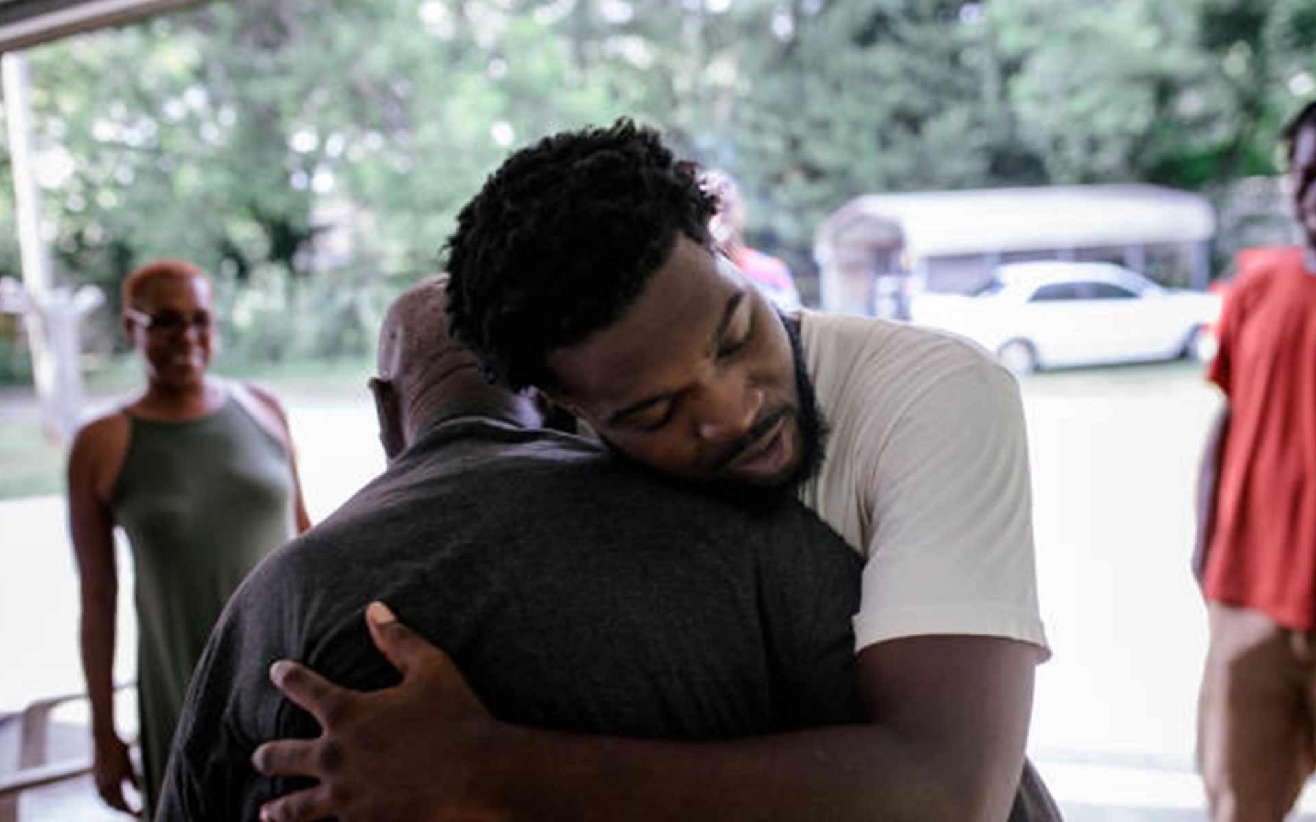 A man is hugging another man in front of a group of people.