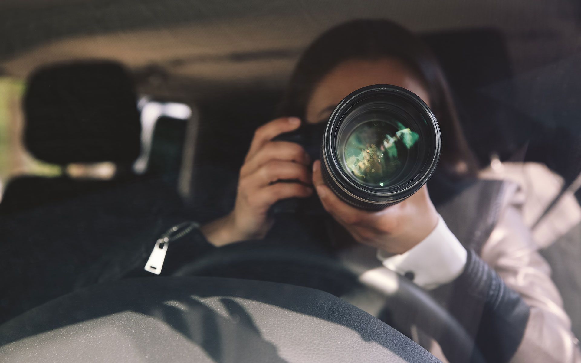 A woman is taking a picture with a camera in a car.