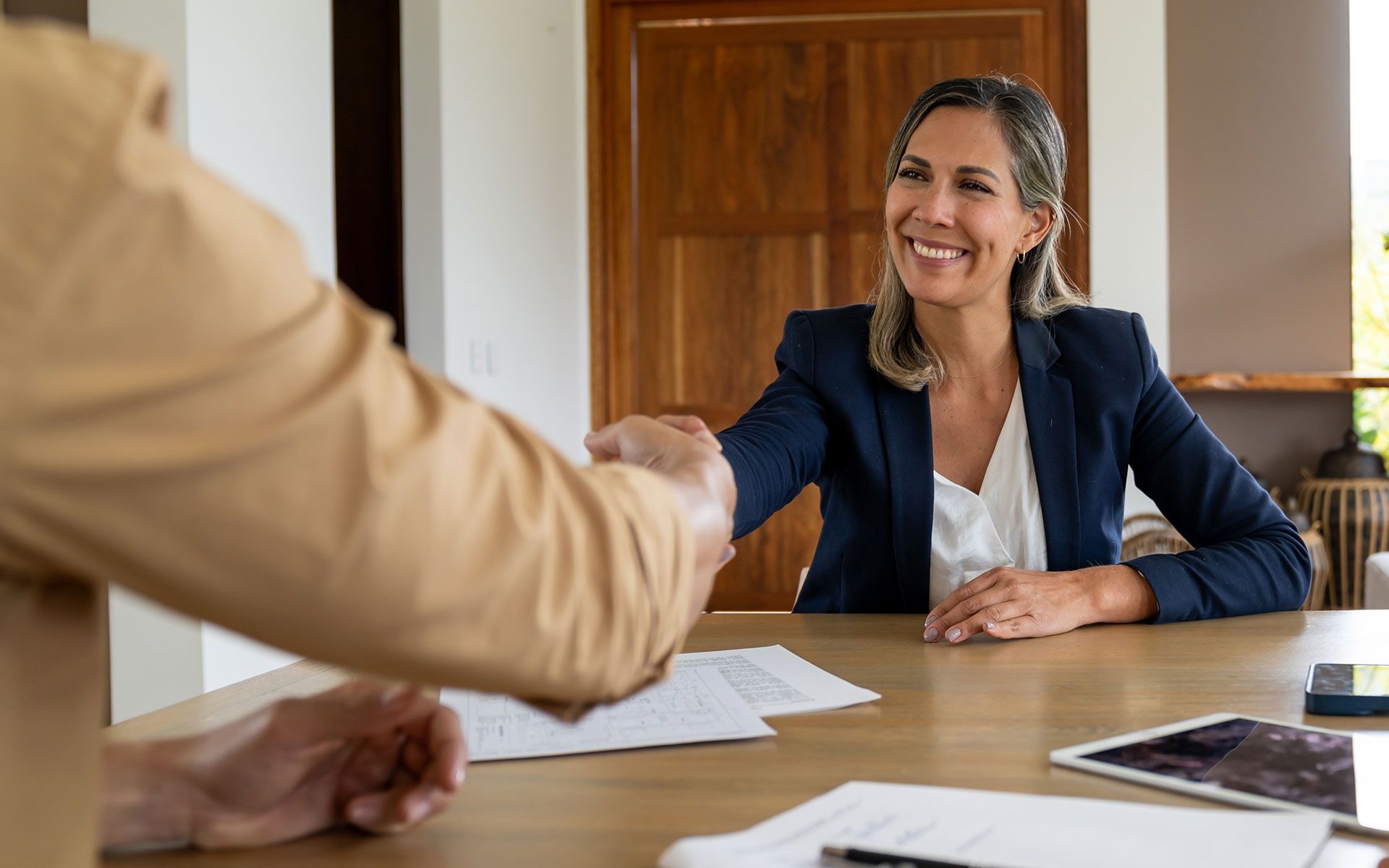 A woman is shaking hands with a man at a table.