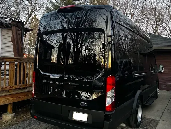 A black van is parked in front of a house.