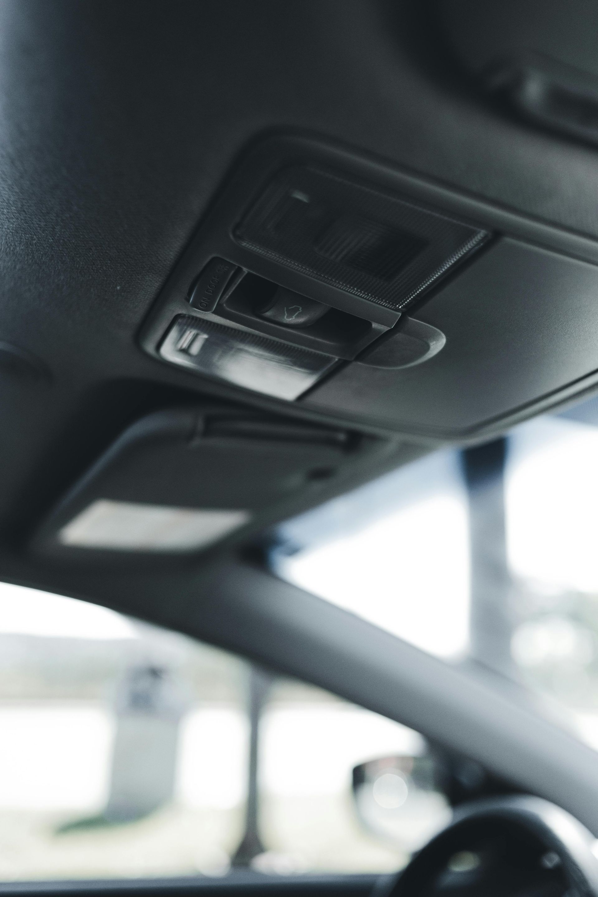 Interior car roof with overhead console and sun visor.