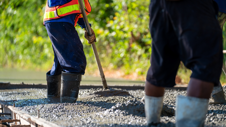 Workers pouring wet concrete over rebar at a construction site