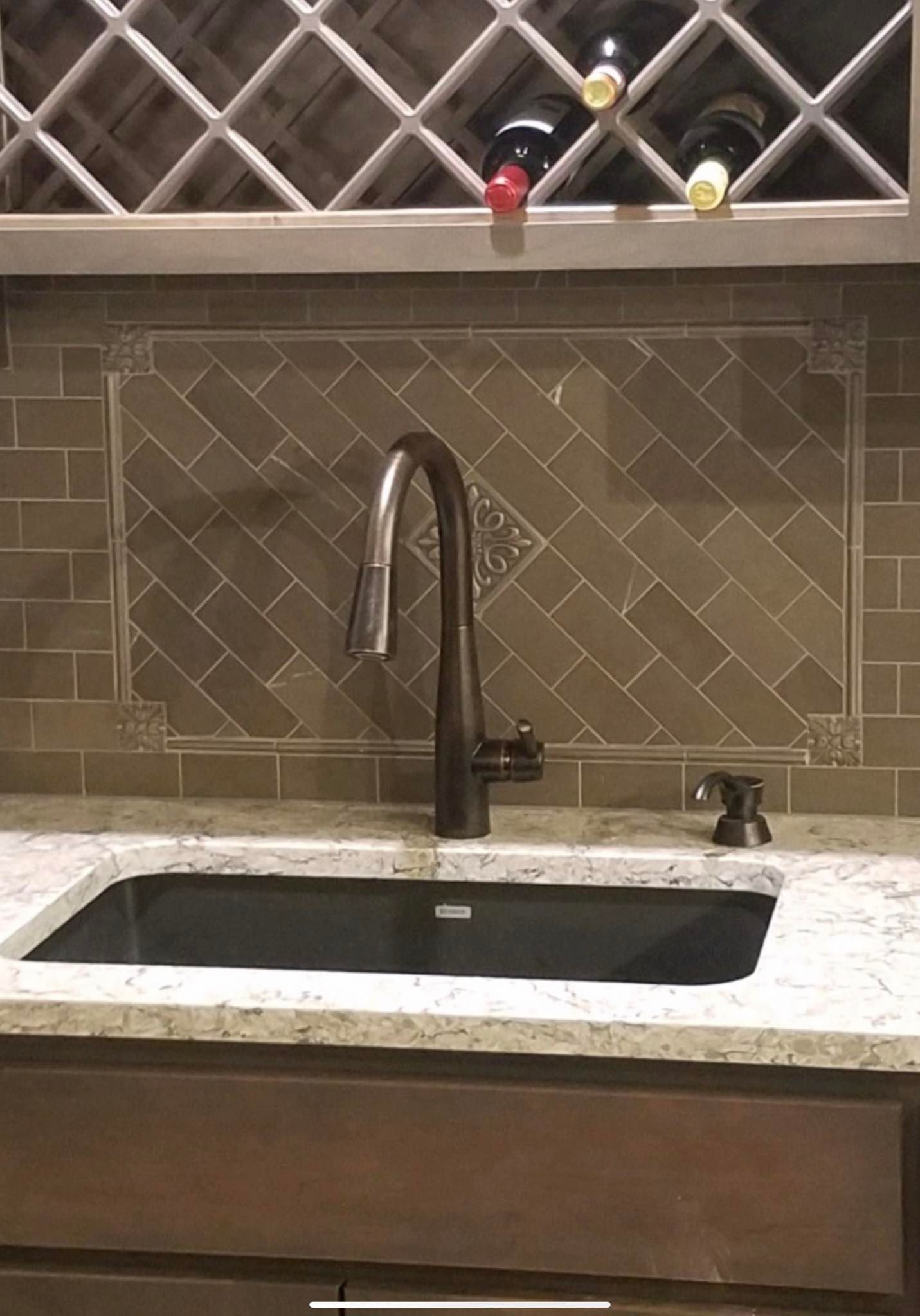 a kitchen sink with a faucet and a wine rack above it .