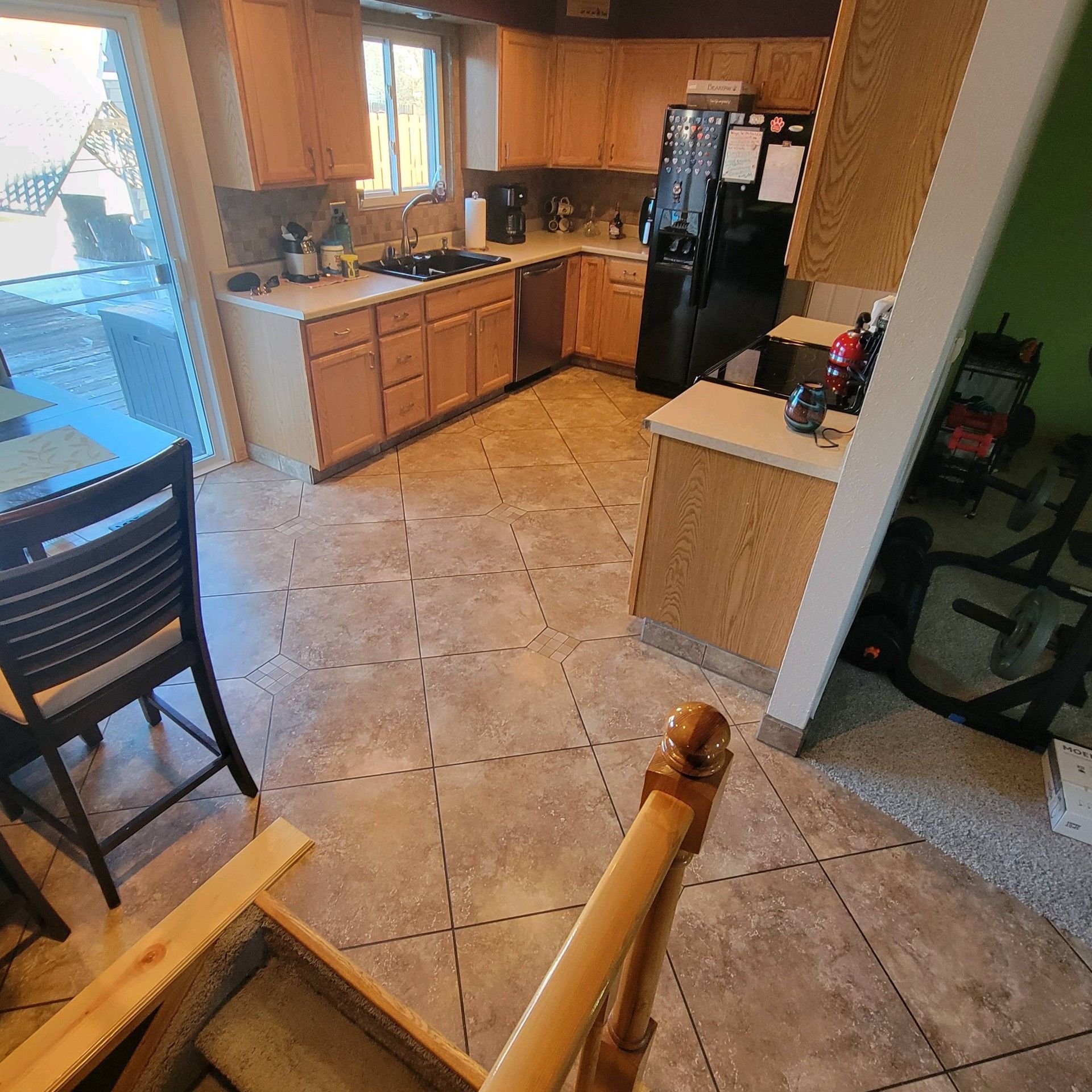 A kitchen with wooden cabinets and a black refrigerator