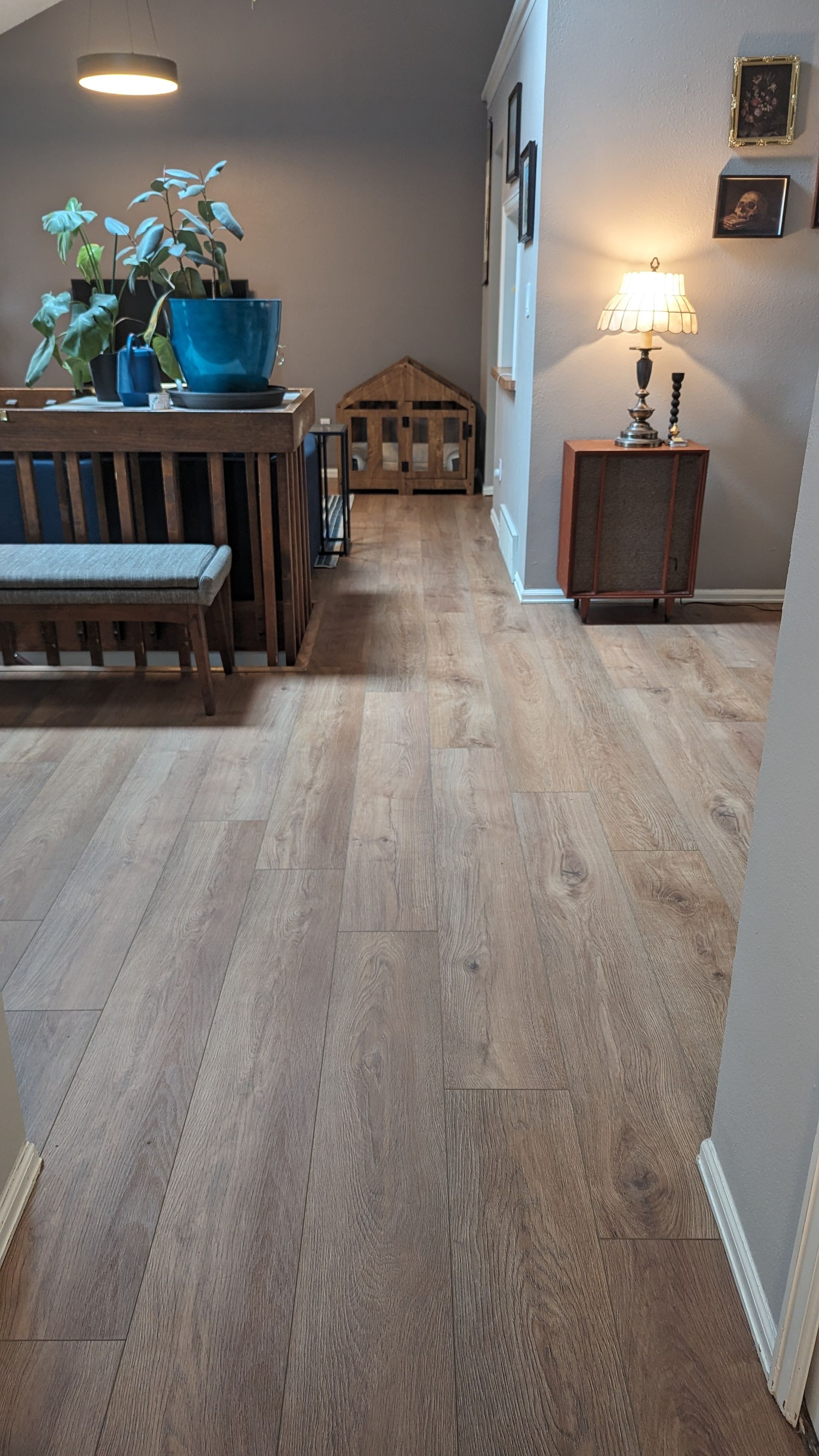 A living room with LVT floors , a table , chairs and a bench.