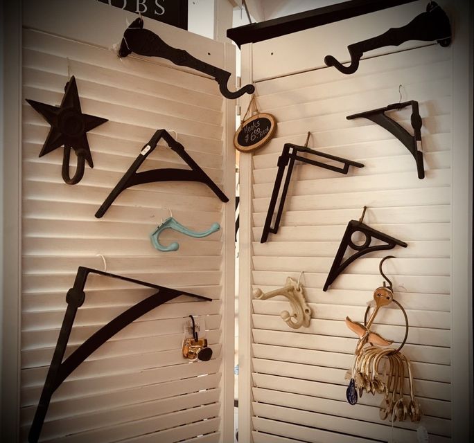 Black metal hooks and brackets displayed on white shuttered doors.