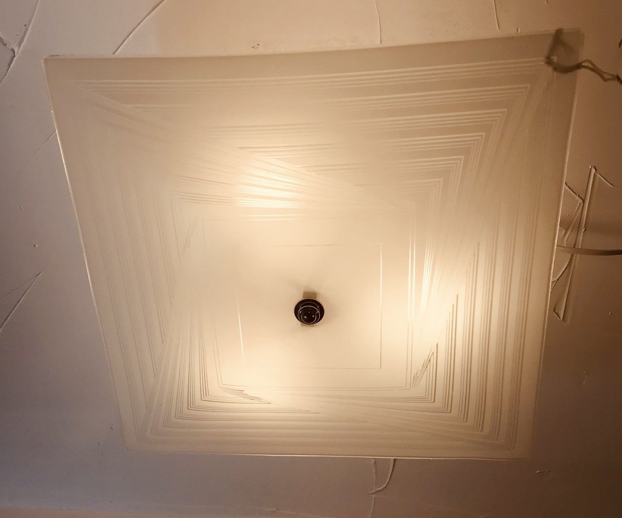 Square, frosted glass ceiling light fixture emitting warm light.