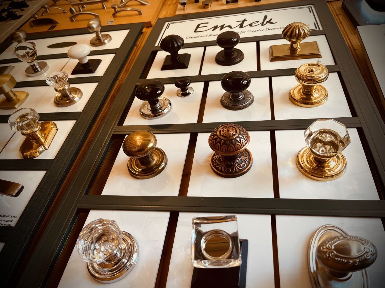 Display of various door knobs in a showroom. Knobs are different shapes, materials, and colors. The brand 