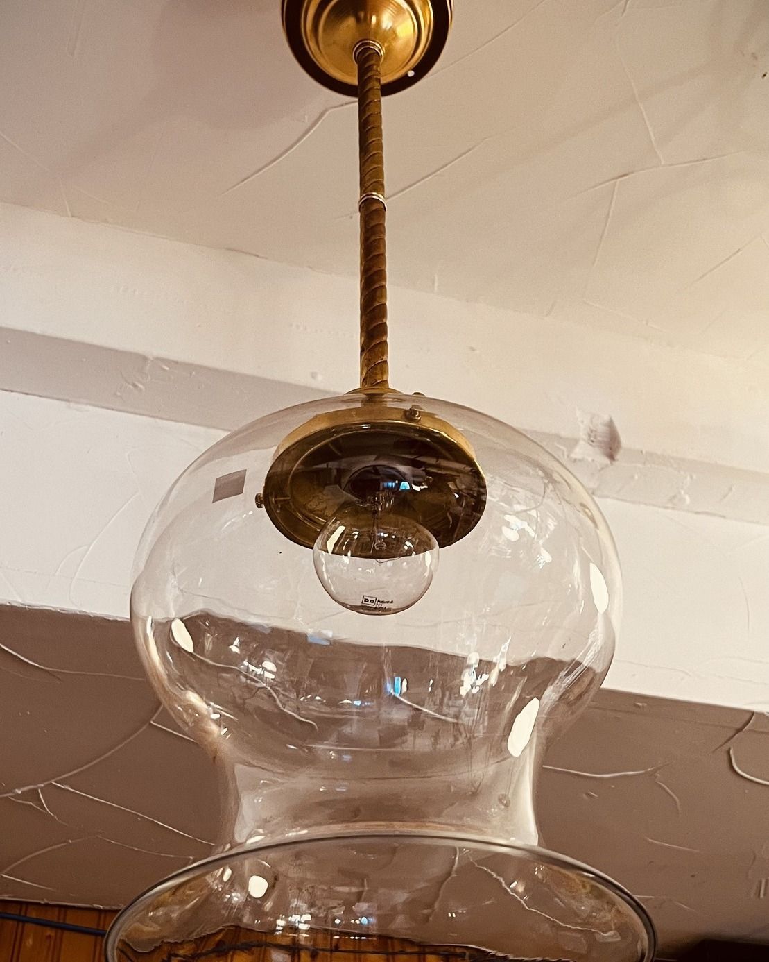 Clear glass pendant light fixture with brass accents, hanging from a ceiling.