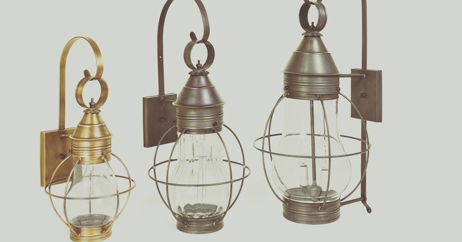 Three metal wall sconces with caged glass bulbs, differing designs, mounted on a neutral background.