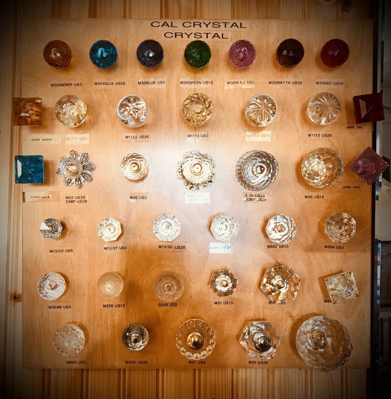 Wooden display board with various colored crystal knobs.