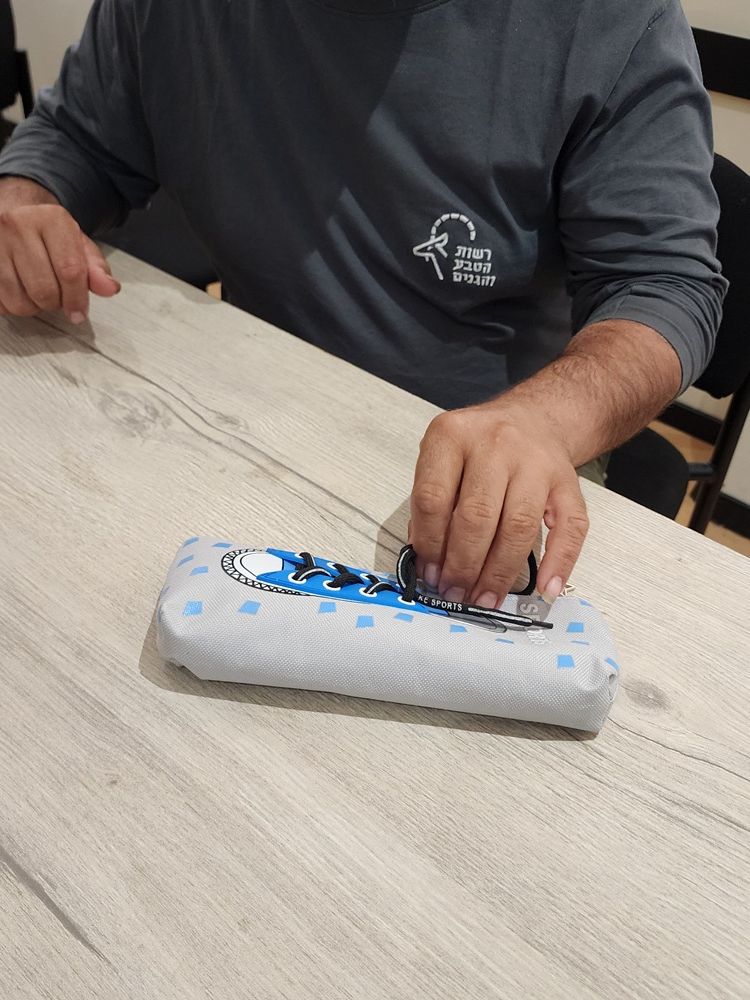 ידיים מסדרות פריט עטוף בכחול-לבן על שולחן באווירה פנימית נינוחה