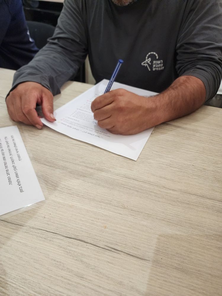 אדם כותב על טופס ליד שולחן עם עט כחול, כשניירות בקרבת מקום.