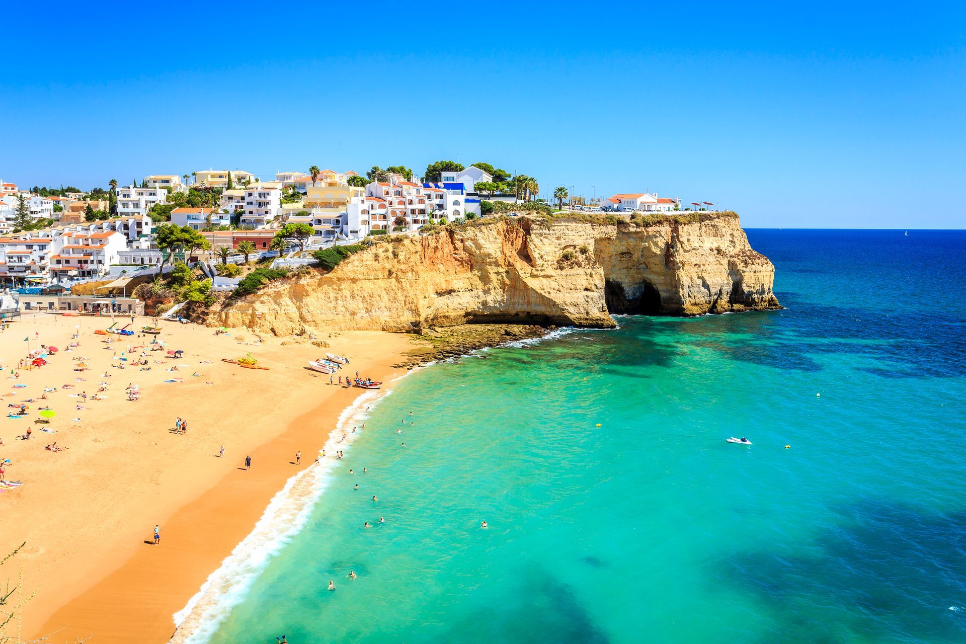 Algarve An aerial view of a beach with a city in the background.