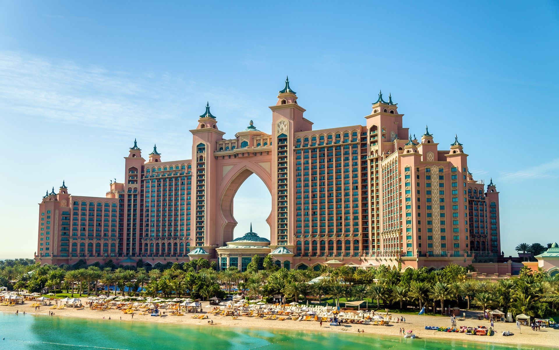 Dubai A large building is sitting on top of a beach next to the ocean.